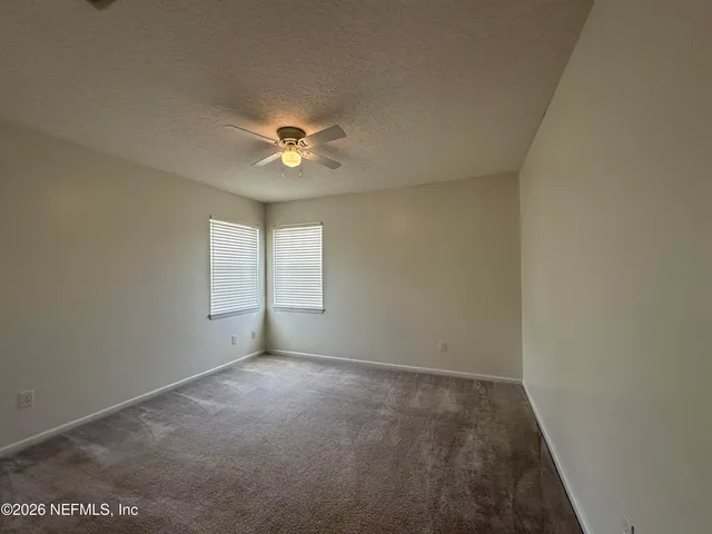 an empty room with windows and a chandelier fan