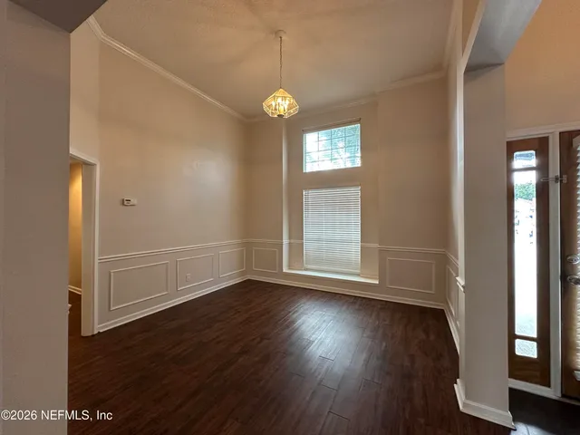 an empty room with wooden floor cabinet and windows