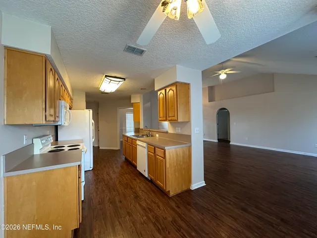 a kitchen with stainless steel appliances granite countertop a sink a stove and a wooden floors