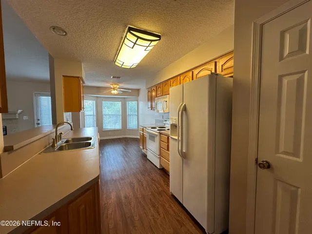 a kitchen with a refrigerator a sink and dishwasher with wooden floor