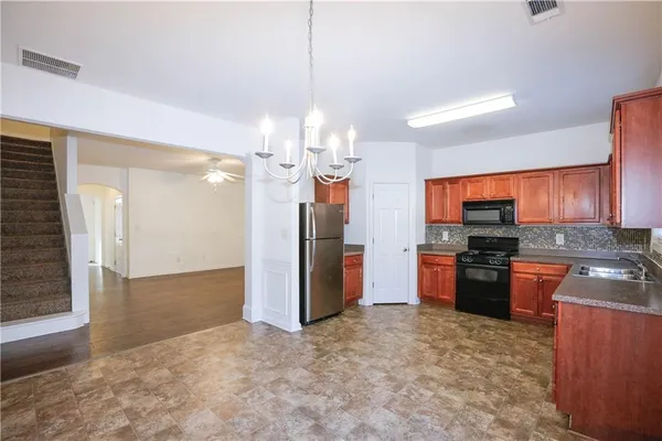 a kitchen with stainless steel appliances granite countertop a refrigerator a oven a sink with a dining table and chairs