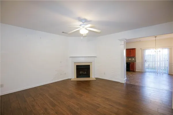 an empty room with wooden floor fireplace and windows