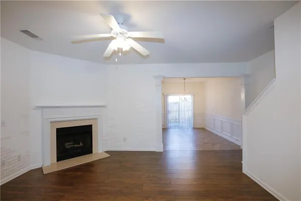a view of an empty room with wooden floor fireplace and a window