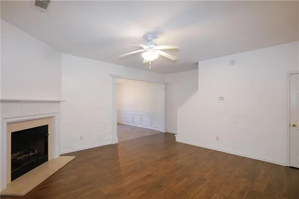 a view of a room with a ceiling fan a fireplace and wooden floor