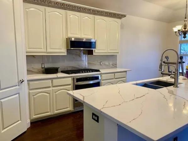 a kitchen with stainless steel appliances white cabinets and wooden floor