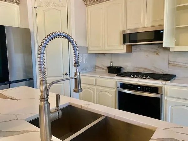 a kitchen with stainless steel appliances a stove a sink and white cabinets