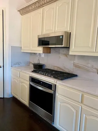 a kitchen with stainless steel appliances granite countertop white cabinets and a stove top oven