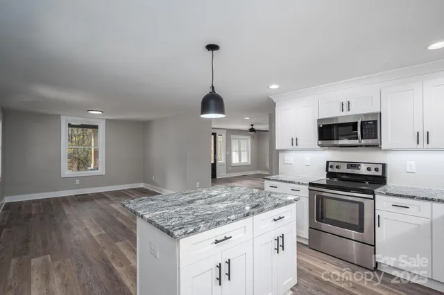 a kitchen with granite countertop a sink stainless steel appliances and white cabinets