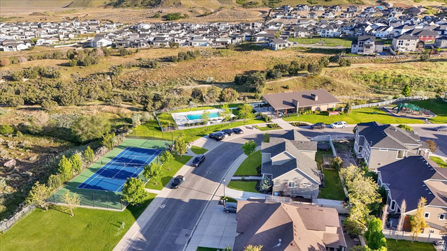 14738 Tangle Hill Road Herriman, UT 84096 - Photo 4 of 66 Aerial perspective of a developed residential community featuring a hard-surface tennis court, a sparkling outdoor swimming pool, and a recreational play structure