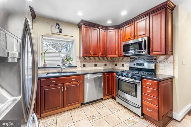 a kitchen with stainless steel appliances granite countertop a stove sink microwave and window