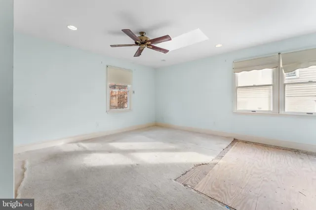 an empty room with windows and fan