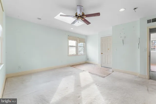 a view of a livingroom with a ceiling fan & windows