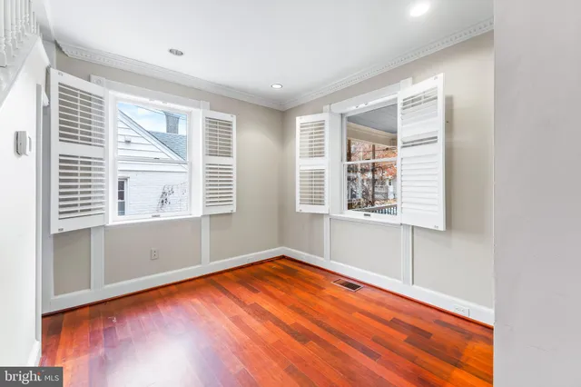 an empty room with wooden floor and windows