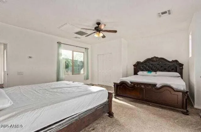 a bedroom with a bed ceiling fan and a window