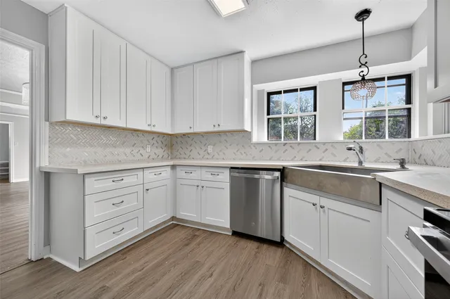 a kitchen with stainless steel appliances granite countertop a sink window and cabinets
