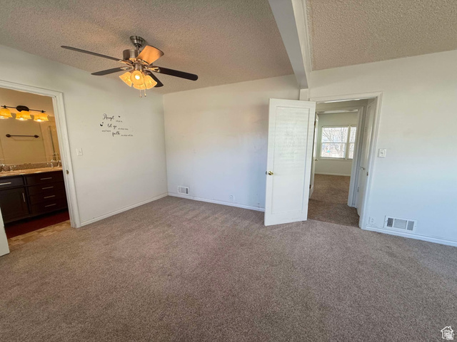 73 Garden Street Helper, UT 84526 - Photo 34 of 36 Unfurnished bedroom with dark carpet, a textured ceiling, ensuite bathroom, a ceiling fan, and beamed ceiling
