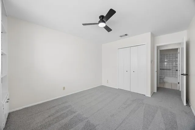 an empty room with a ceiling fan and window