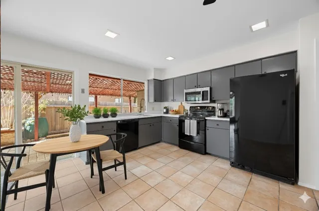a kitchen with a refrigerator a stove top oven and a dining table with wooden floor
