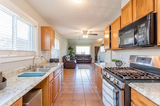a kitchen with stainless steel appliances granite countertop a stove a sink and a microwave