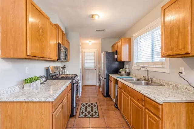 a kitchen with granite countertop kitchen island stainless steel appliances a sink stove and cabinets