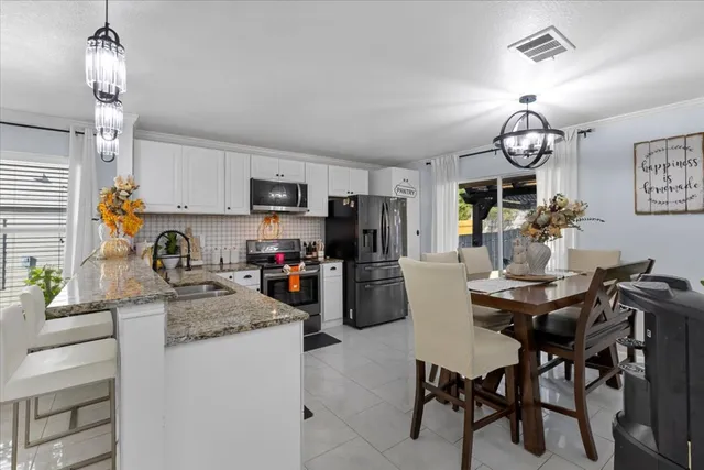 a kitchen with sink a refrigerator and chairs