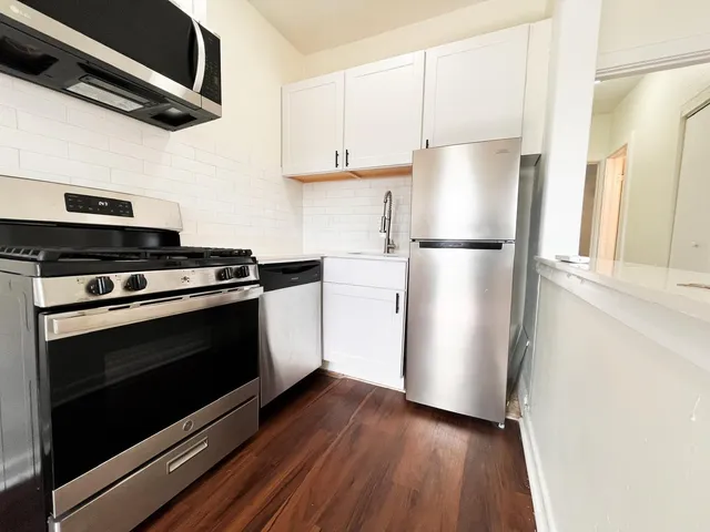 a kitchen with a refrigerator stove and white cabinets
