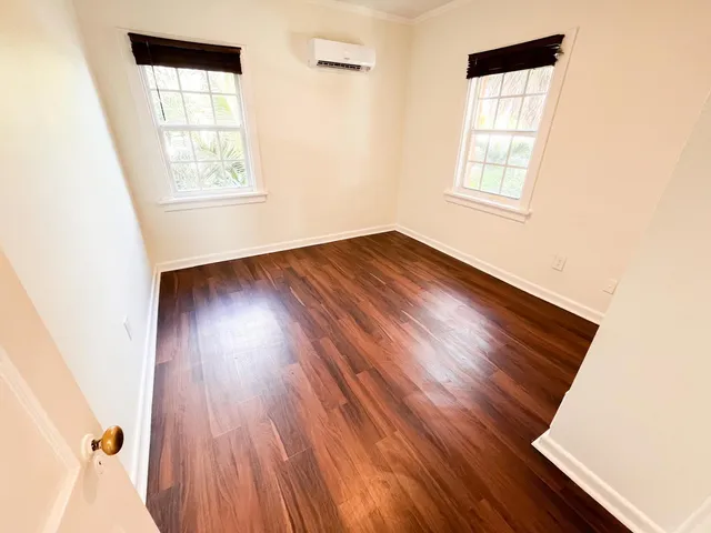 an empty room with wooden floor and windows