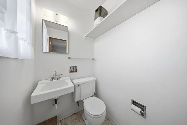 a bathroom with a toilet a sink and mirror