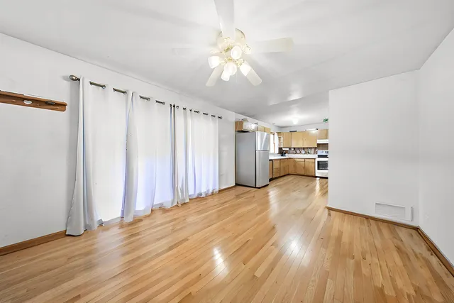 a view of a room with wooden floor staircase and a ceiling fan