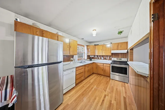 a kitchen with a refrigerator a sink and dishwasher with wooden floor