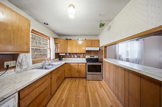 a kitchen with a sink a counter top space stainless steel appliances cabinets and a large window