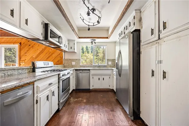 a kitchen with stainless steel appliances a white cabinets and wooden floors