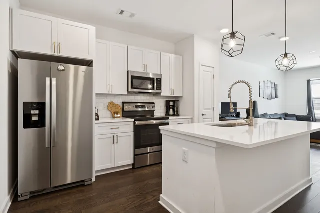 a kitchen with stainless steel appliances granite countertop a refrigerator a stove a sink and a refrigerator