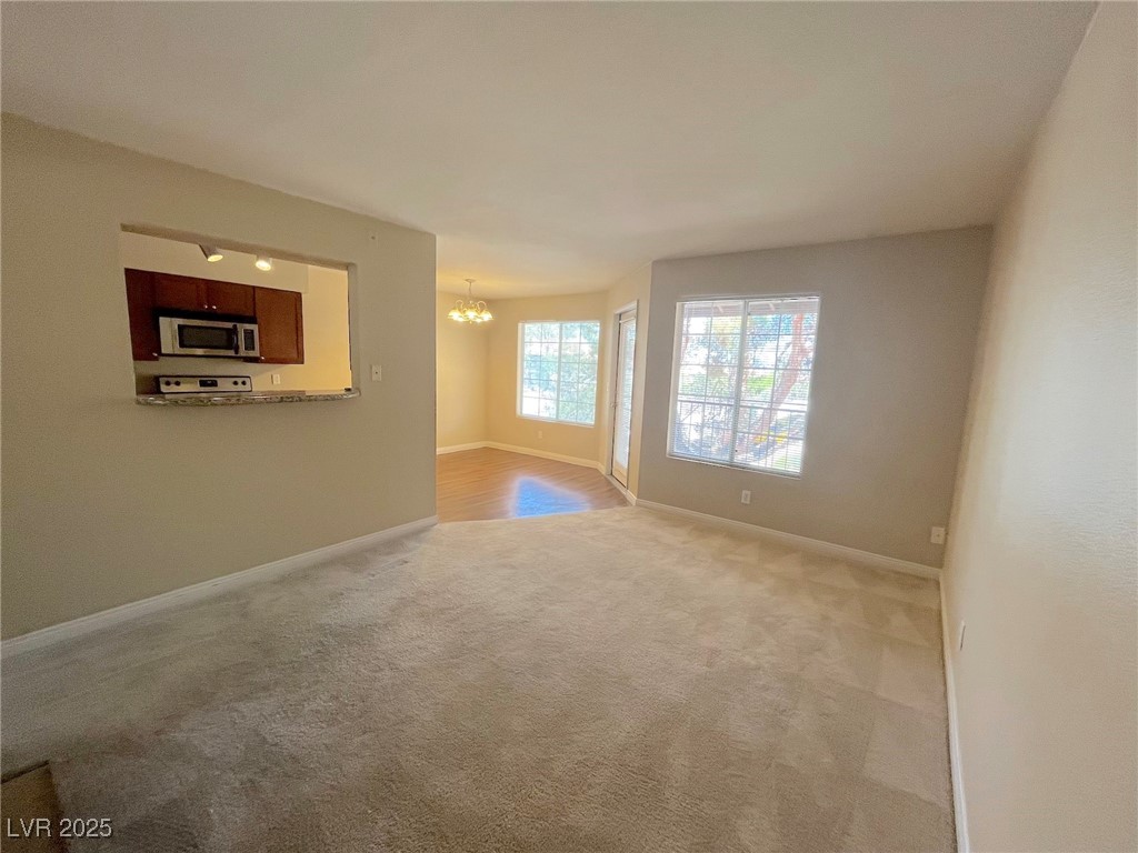 Unfurnished living room featuring a chandelier and carpet floors
