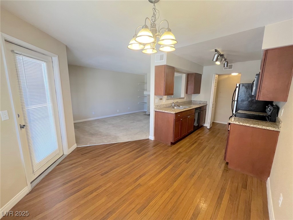 2750 South Durango Drive, Unit 2139 Las Vegas, NV 89117 - Photo 21 of 21 Kitchen featuring light stone counters, pendant lighting, light wood-style flooring, open floor plan, and a chandelier