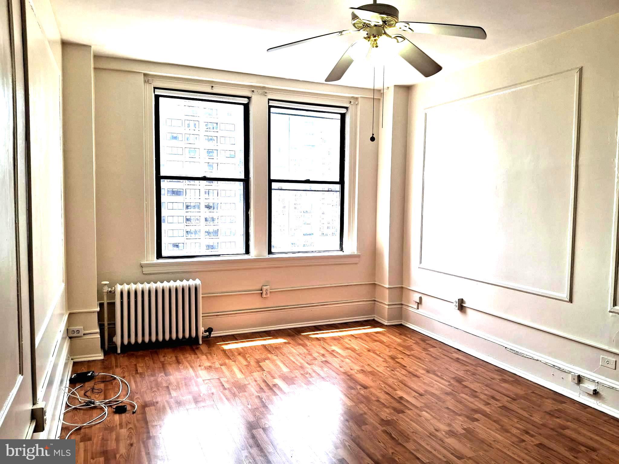 1324 Locust Street, Unit 1421 Philadelphia, PA 19107 - Photo 1 of 15 a view of an empty room with a window and wooden floor