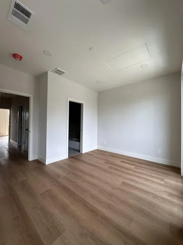 a kitchen with stainless steel appliances kitchen island granite countertop a stove a sink a refrigerator and white cabinets with wooden floor