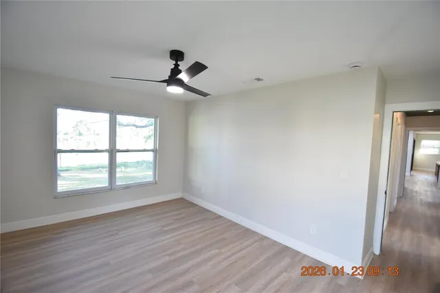 an empty room with wooden floor fan and windows