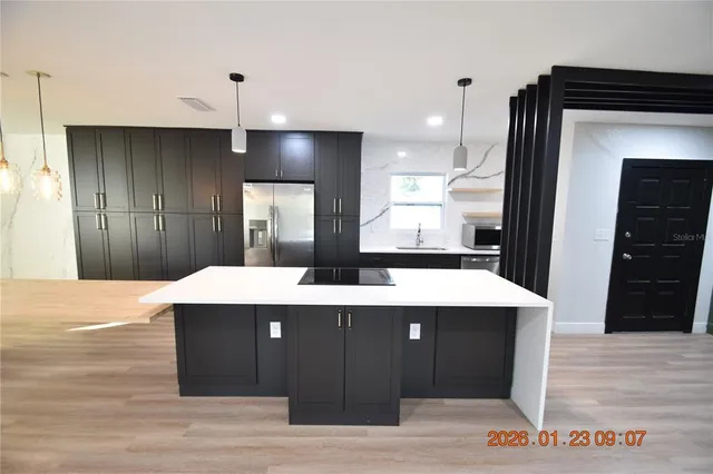 a kitchen with kitchen island stainless steel appliances kitchen island sink refrigerator and stove