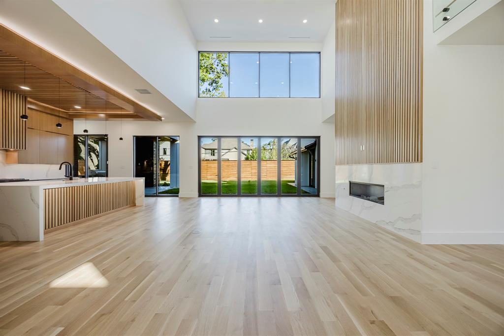 5723 Meletio Lane Dallas, TX 75230 - Photo 7 of 38 Unfurnished living room featuring light wood finished floors, recessed lighting, a premium fireplace, and a high ceiling