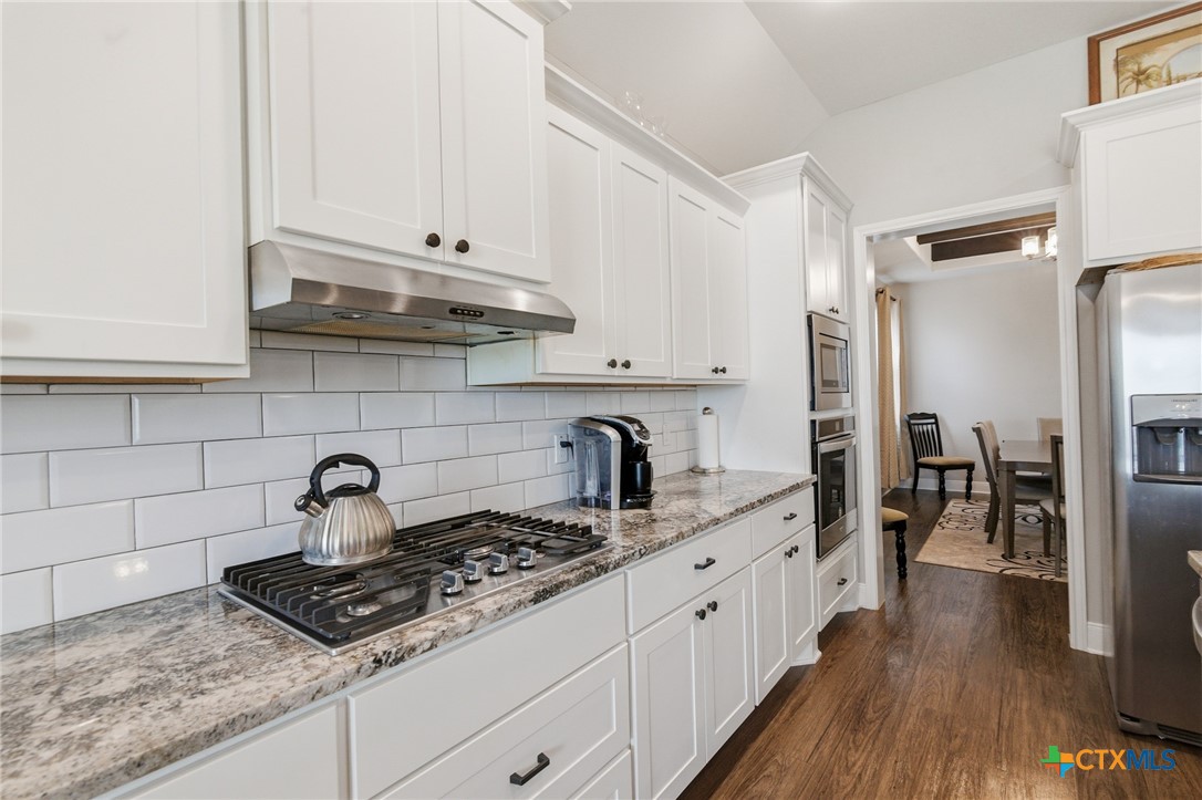 113 Terra Vista Ranch Road Victoria, TX 77904 - Photo 20 of 47 a kitchen with stainless steel appliances granite countertop a stove a sink dishwasher and white cabinets with wooden floor