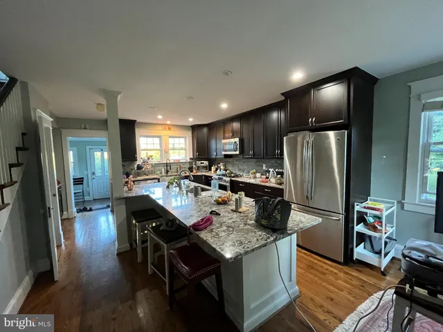 a kitchen with stainless steel appliances granite countertop a refrigerator a stove a sink a dining table and chairs