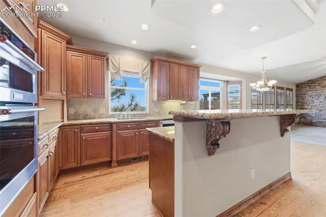 a kitchen with stainless steel appliances granite countertop a refrigerator a sink dishwasher a stove with wooden cabinets and floor