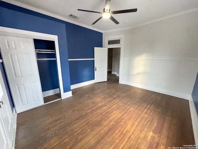 a view of empty room with wooden floor and fan