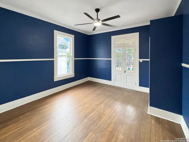 an empty room with wooden floor and windows