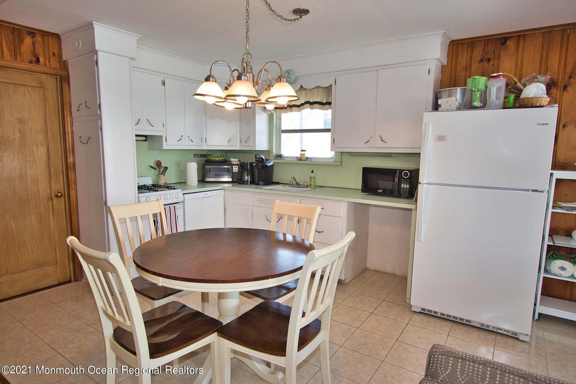 1 Brooklyn Avenue Lavallette, NJ 08735 - Photo 32 of 55 a kitchen with stainless steel appliances granite countertop a dining table chairs a refrigerator and a chandelier