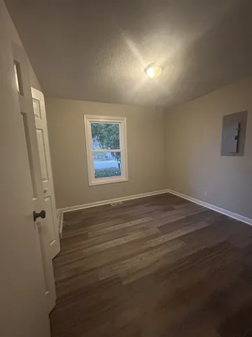 a view of an empty room with wooden floor and a window