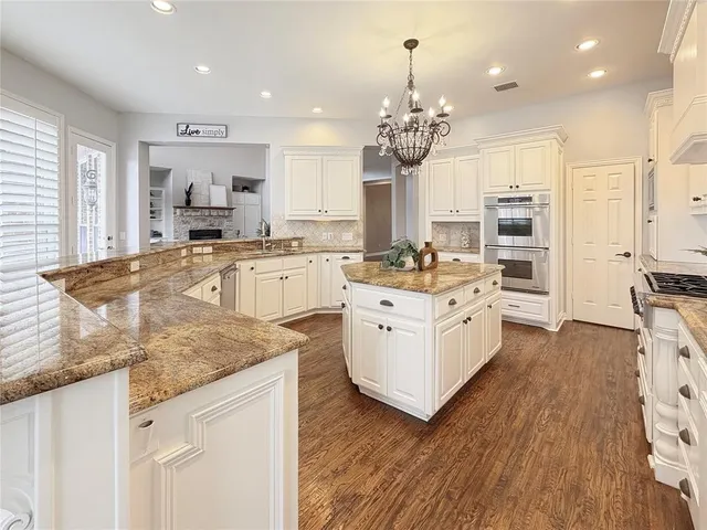 a kitchen with stainless steel appliances granite countertop a oven a stove cabinets and wooden floor