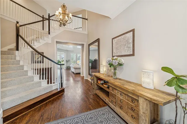 a view of a hallway with wooden floor staircase and livingroom