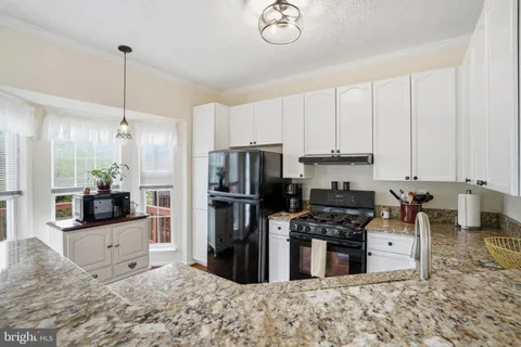 a kitchen with kitchen island granite countertop a stove a refrigerator a sink a oven with a dining table and chairs